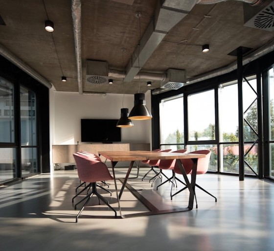 Sunlit modern meeting room with wooden table and pink chairs